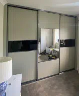 3 door sliding wardrobe with the outer doors having larger sage green panels and a small strip of black glass divider and the middle having a large mirror in the center and smaller sage green top and bottom, fitted in Yarm